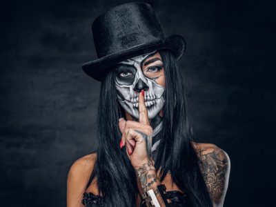 Female in Halloween silence. A woman in top hat and skull make up.